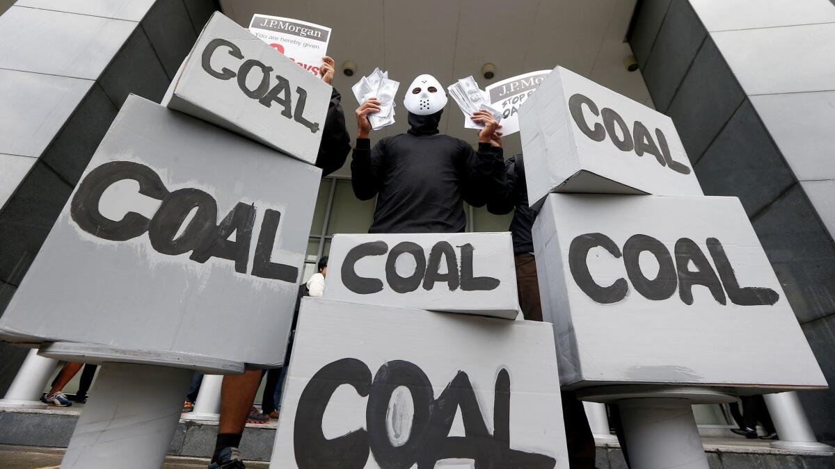 A masked environmental activist wags mock dollars bills during a protest outside the JP Morgan Chase & Co. office to urge the multi-national company to stop its funding of a coal-fired power plant in the country.