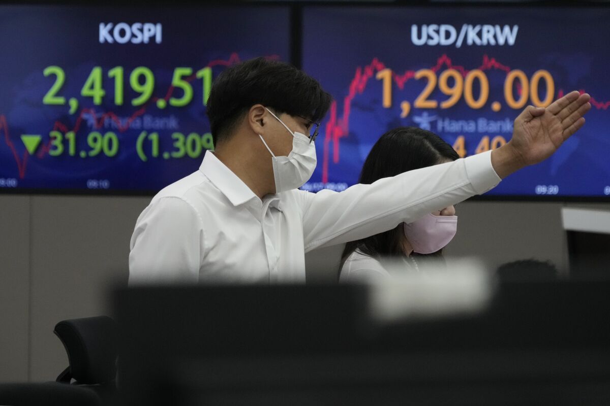 A currency trader gestures in front of the screens showing the Korea Composite Stock Price Index (KOSPI), left, and the exchange rate of South Korean won against the U.S. dollar at the foreign exchange dealing room of the KEB Hana Bank headquarters in Seoul, South Korea, Friday, June 17, 2022. Asian stock markets were mostly lower Friday after Wall Street fell on fears interest rate hikes will depress global economic activity. (AP Photo/Ahn Young-joon)