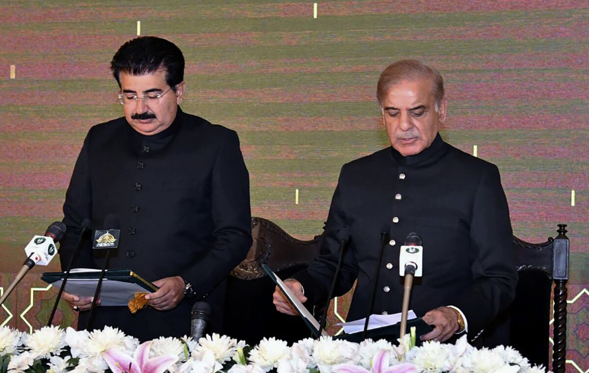 FILE - In this photo released by Press Information Department, acting President of Pakistan Sadiq Sanjrani, left, administers the oath of office to newly elected Pakistani Prime Minister Shahbaz Sharif at Presidential Palace, in Islamabad, Pakistan, Monday, April 11, 2022. Sharif appeared in court on Monday, June 21, 2022, in connection with an old corruption case and was granted exemption from further appearances in person in the hearings, his defense lawyer said. The case dating back four years is related to Sharif's alleged links to a multi-million dollar housing scam in the eastern city of Lahore, according to the attorney, Amjad Pervez. (Press Information Department via AP, File)