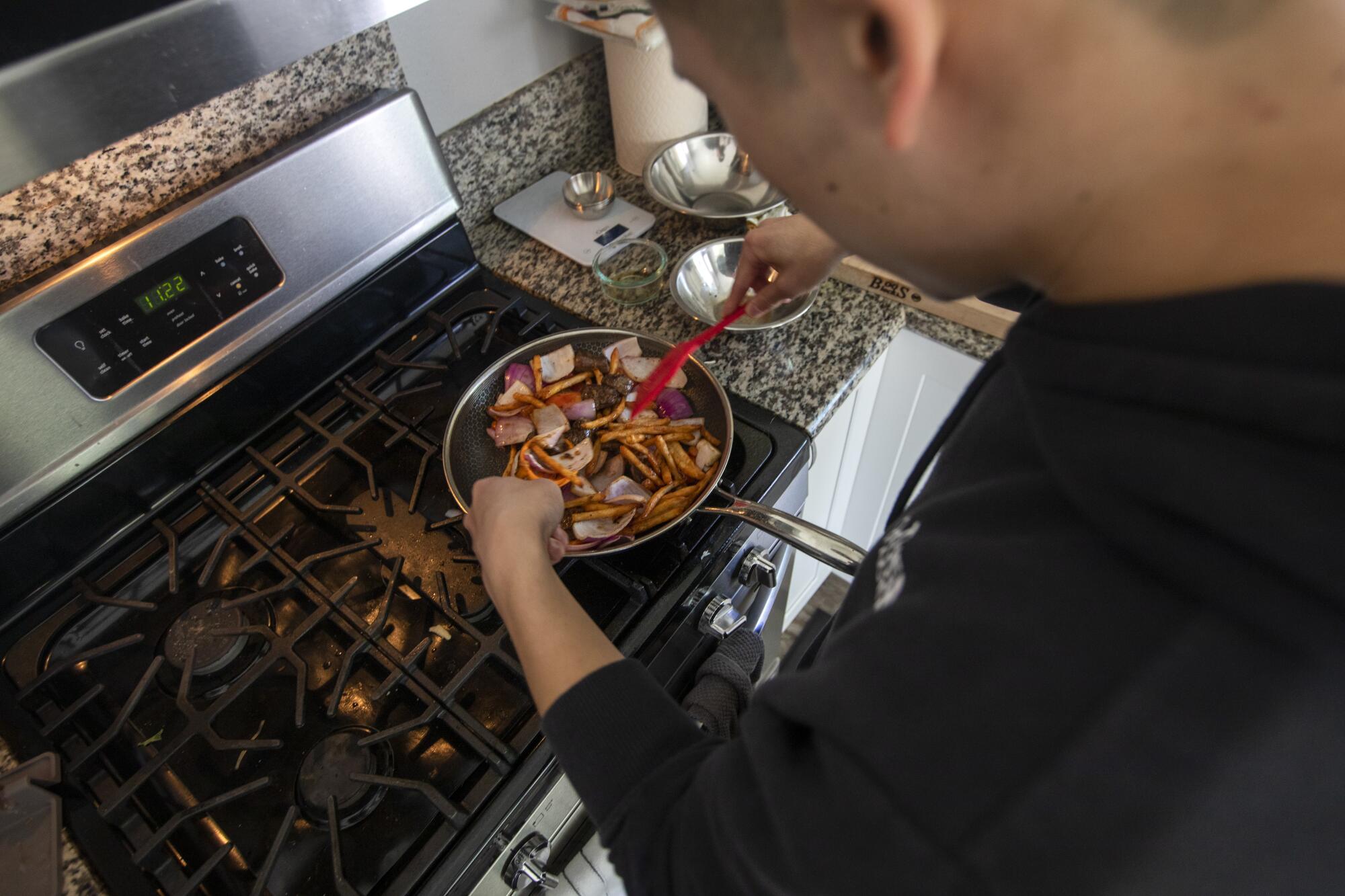 Ryan Fung stirs food  on a stove