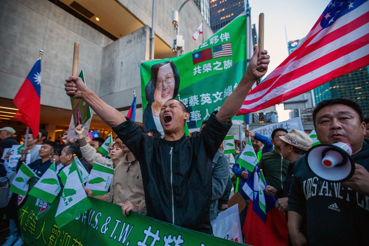 A protester shouts in front of a banner depicting Taiwanese President Tsai Ing-wen.
