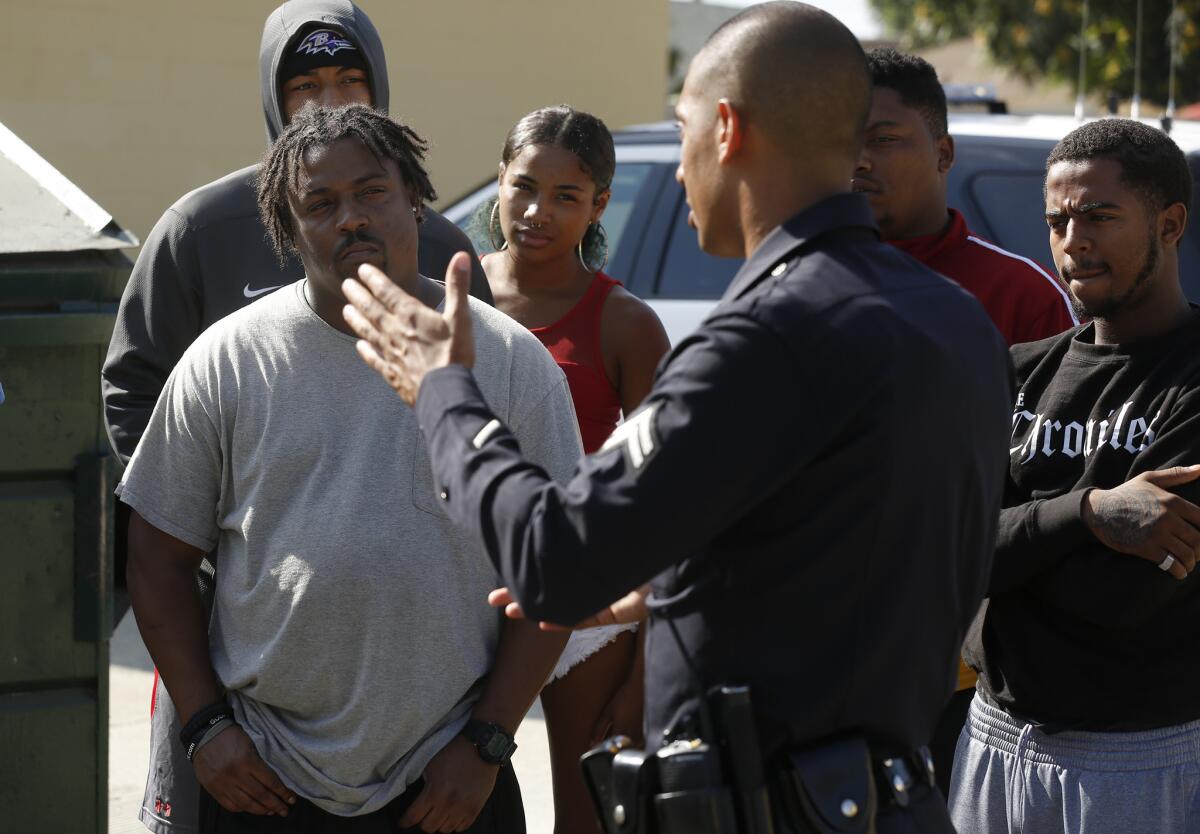 Los Angeles Police Officer Aaron Thompson talks with Richard Risher, left, the father of an 18-year-old man killed Monday night at the Nickerson Gardens housing project in Watts.