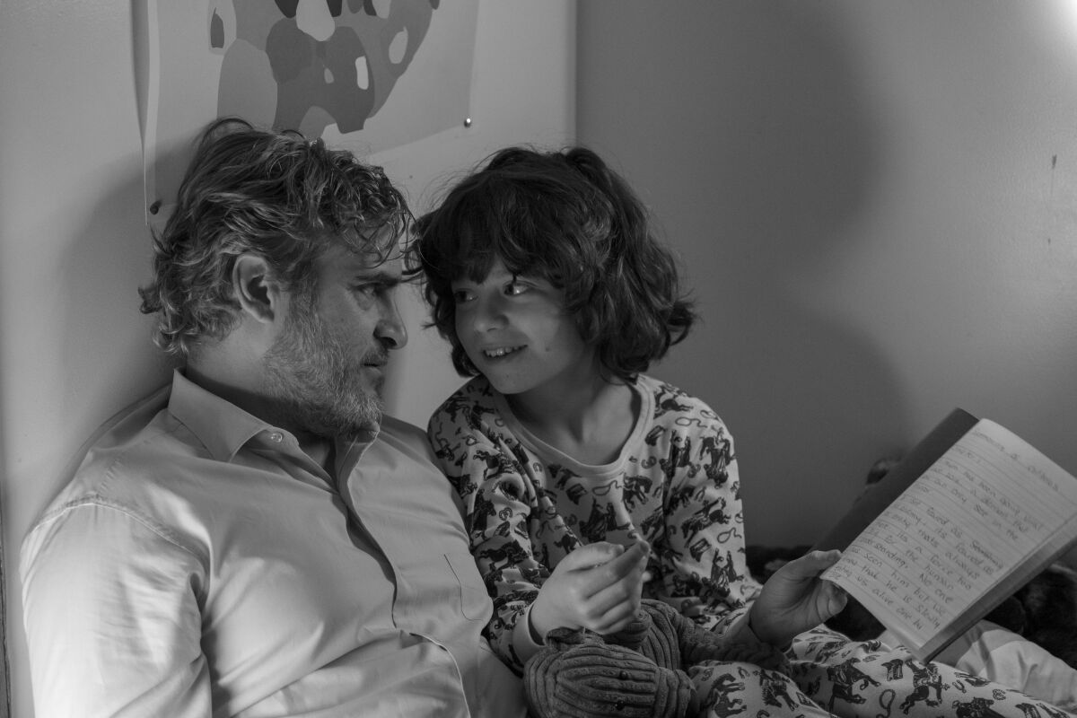 Joaquin Phoenix cuddles up to young Woody Norman in a scene from “C’mon C’mon.”