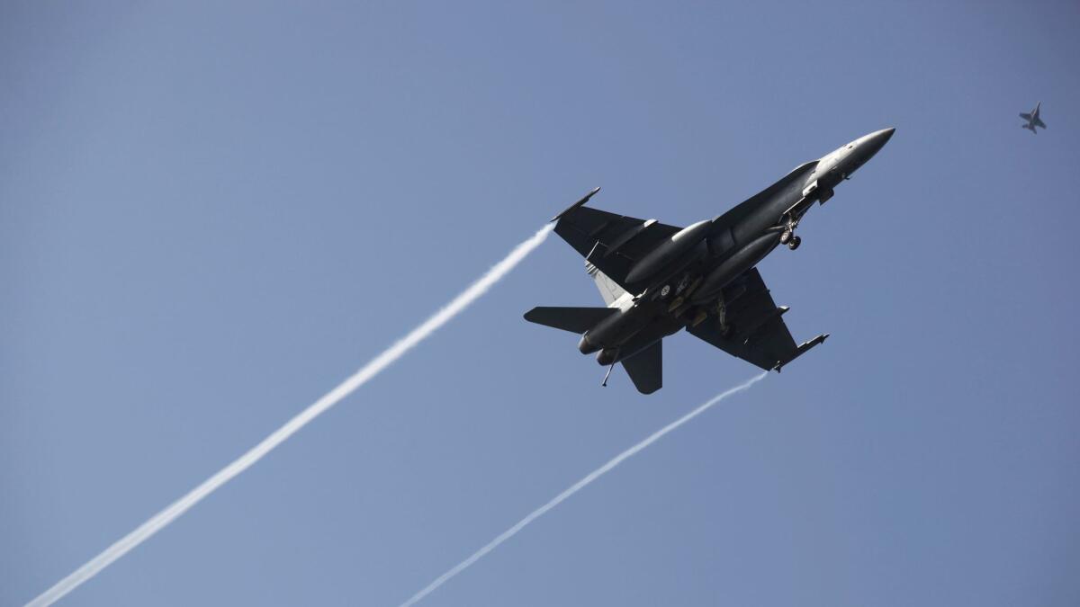 An F-18 fighter jet flies over the USS George H.W. Bush as the ship travels toward the Strait of Hormuz in March.