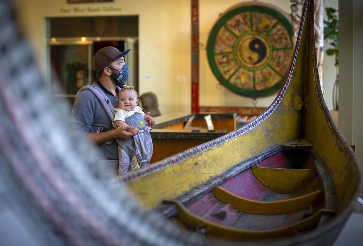 A father and his 6-month-old son stroll among artifacts and art at Bowers Museum.