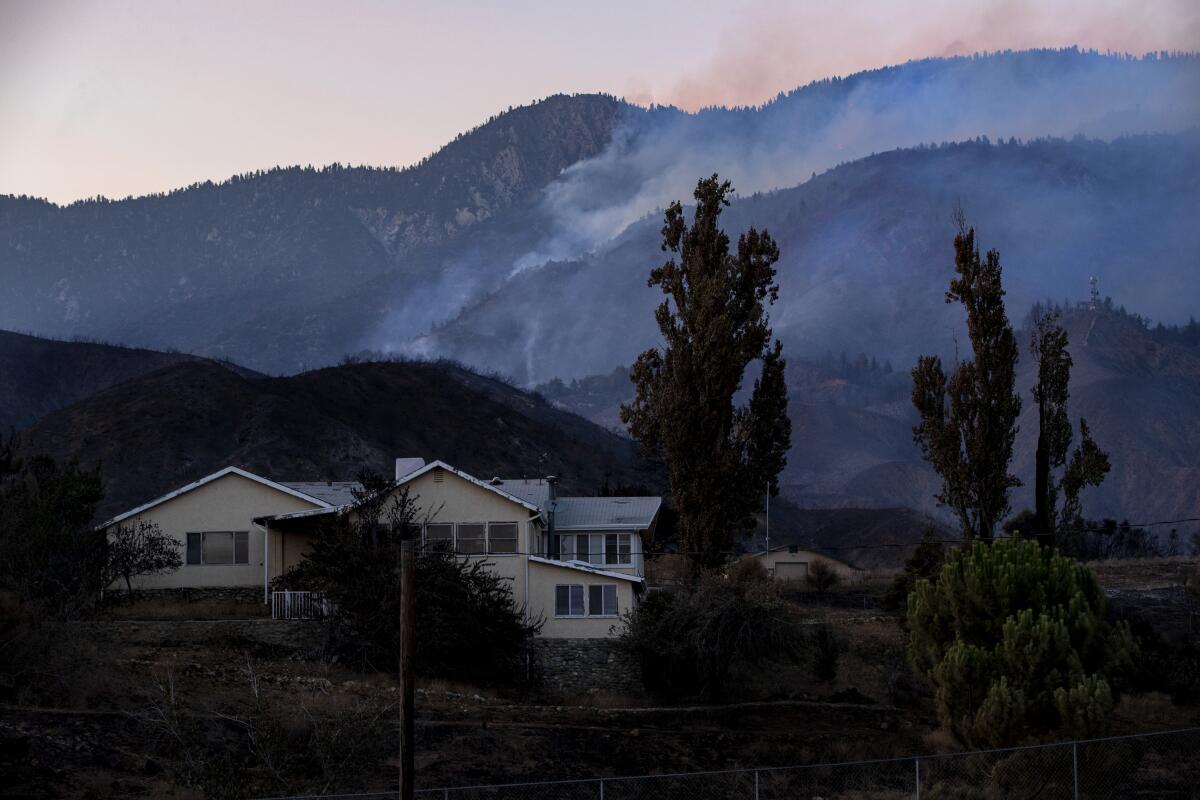 Scorched terrain surrounds a home off Bluff Street in Banning, Calif., as the Apple fire smolders Tuesday.