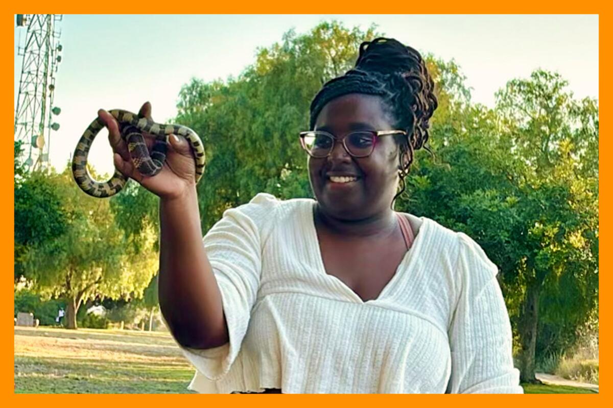 Earyn McGee smiles while holding a California king snake, a nonvenomous native reptile.