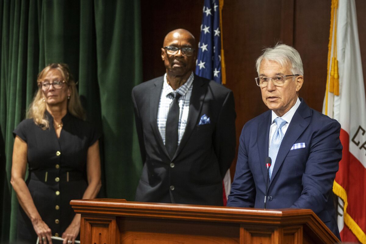 Maurice Hastings and an unidentified woman look on as L.A. County Dist. Atty. George Gascón speaks
