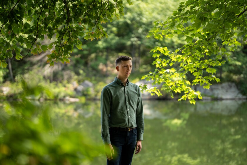 Grayson Badgley, in a green shirt, stands surrounded by trees