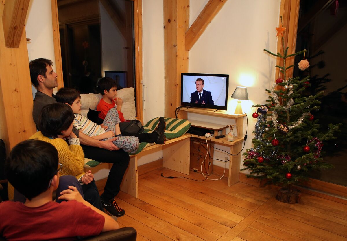 The Taberna family watch French President Emmanuel Macron give an interview on television, in Ascain, southwestern France, Wednesday, Dec. 15, 2021. French President Emmanuel Macron is expected to defend his actions during his presidency in a long interview Wednesday on national television, in a bid to boost his popularity ahead of April’s presidential election. (AP Photo/Bob Edme)