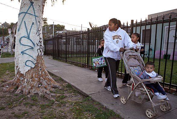 A young family passes a graffiti-scarred tree on Drew Street near Estara Avenue in Glassell Park. The secluded thoroughfares are "hands down the worst area of Northeast Division," said LAPD Officer Steve Aguilar, who has patrolled the neighborhood for several years. "I've worked two other divisions and even in South-Central. This is worse." Neighbors, mostly Latino immigrants, endure it like a conquered people: indoors, not speaking to one another, afraid.