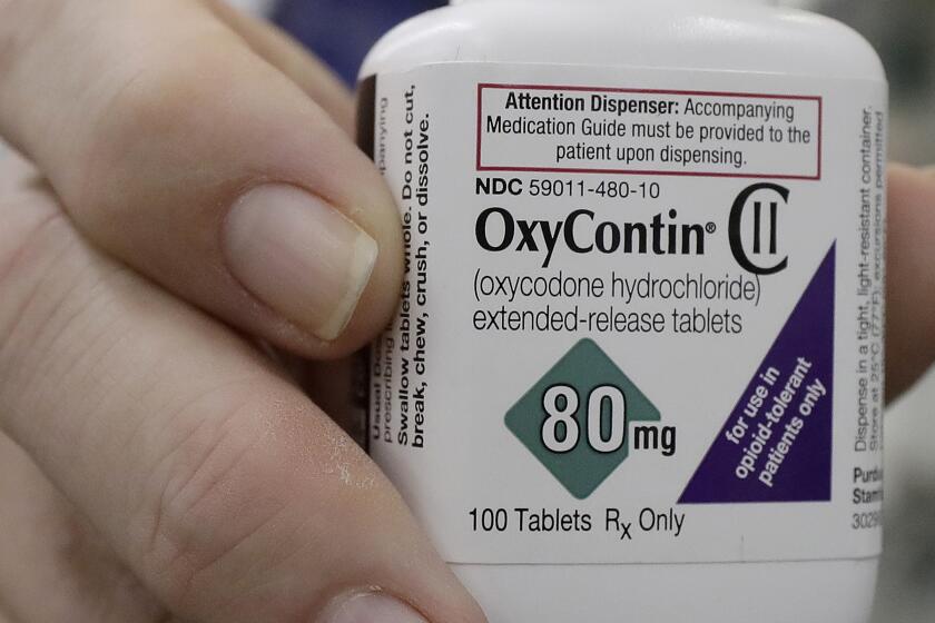 FILE - In this April 2, 2018, file photo, a pharmacist in San Francisco poses for photos holding a bottle of OxyContin. In court papers filed in New York on Sunday, Sept. 15, 2019, Purdue Pharma, the drug's manufacturer, flied for Chapter 11 bankruptcy protection. (AP Photo/Jeff Chiu, File)