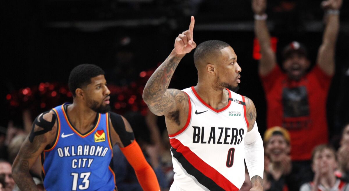 Trail Blazers guard Damian Lillard, right, reacts after making a basket against Thunder forward Paul George