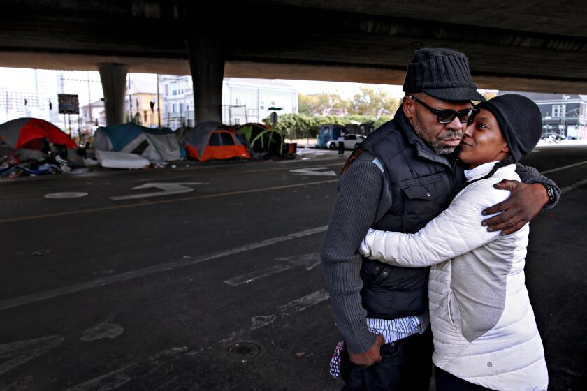 OAKLAND, CA - OCT. 9: Raymond Joseph, 56, holds his fianceé Regina Carter, 40, at their encampment off of Martin Luther King Jr Way and 23rd Street in Oakland, Calif., on Friday, October 9, 2020. The couple are expecting a baby in seven months. The couple would like to have permanent housing before their baby arrives. Oakland is in the midst of the worst homelessness crisis the city has ever seen. Overall homelessness in Oakland increased by 47% with a 68% increase from 2017 to 2019 in the number of unsheltered people from 1,902 to 3,210 people. There are an estimated 60 encampments of three or more people in Oakland with approximately 730 total people living in the encampments. (Yalonda M. James/The San Francisco Chronicle via Getty Images)