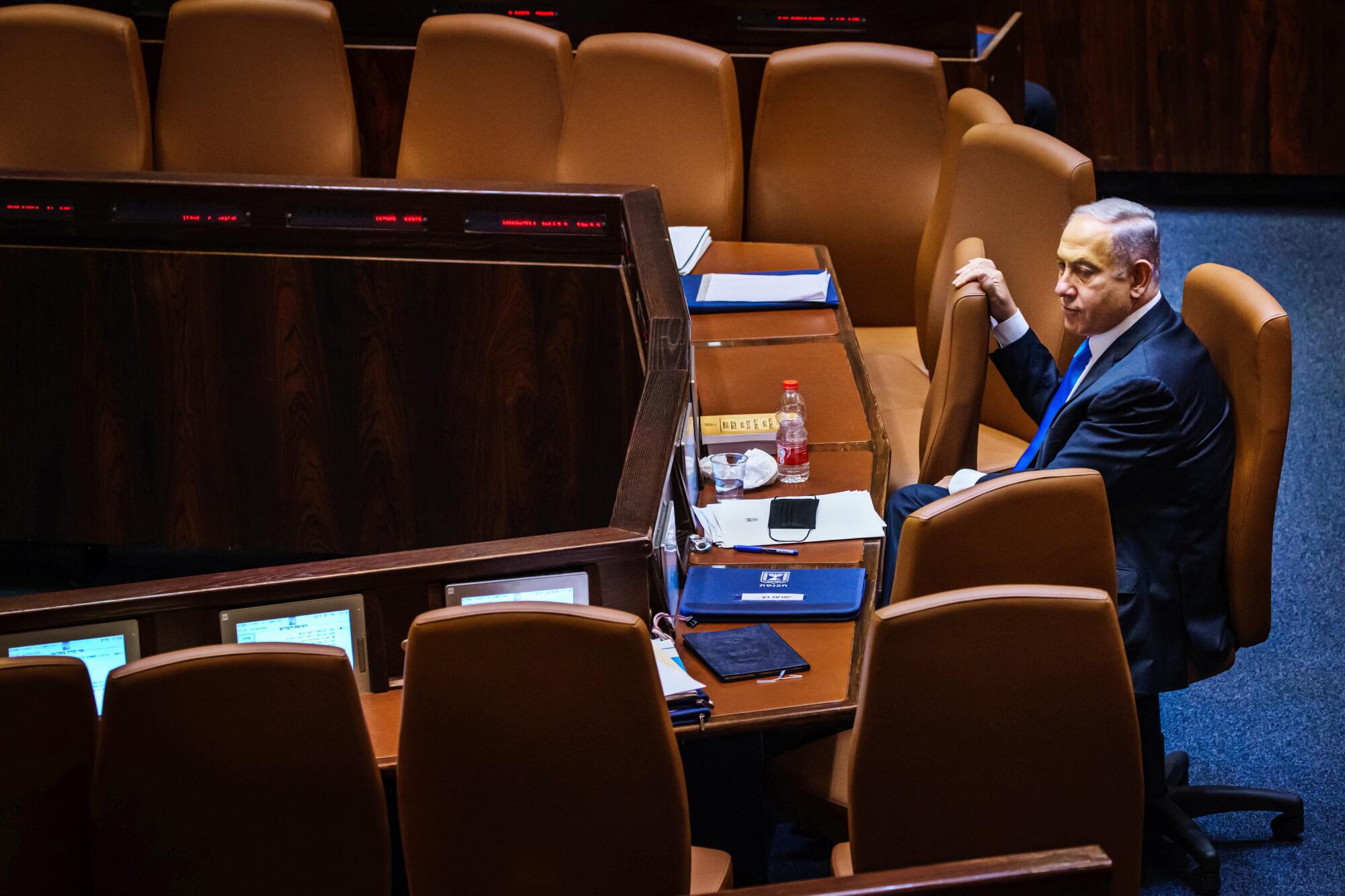 Outgoing Prime Minister Benjamin Netanyahu takes a look around the empty seats as members of the Knesset.