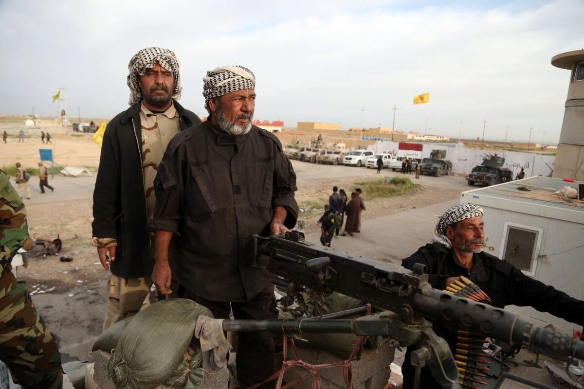 Shiite Muslim militiamen take combat positions at the front line in Tikrit, Iraq, on March 12.