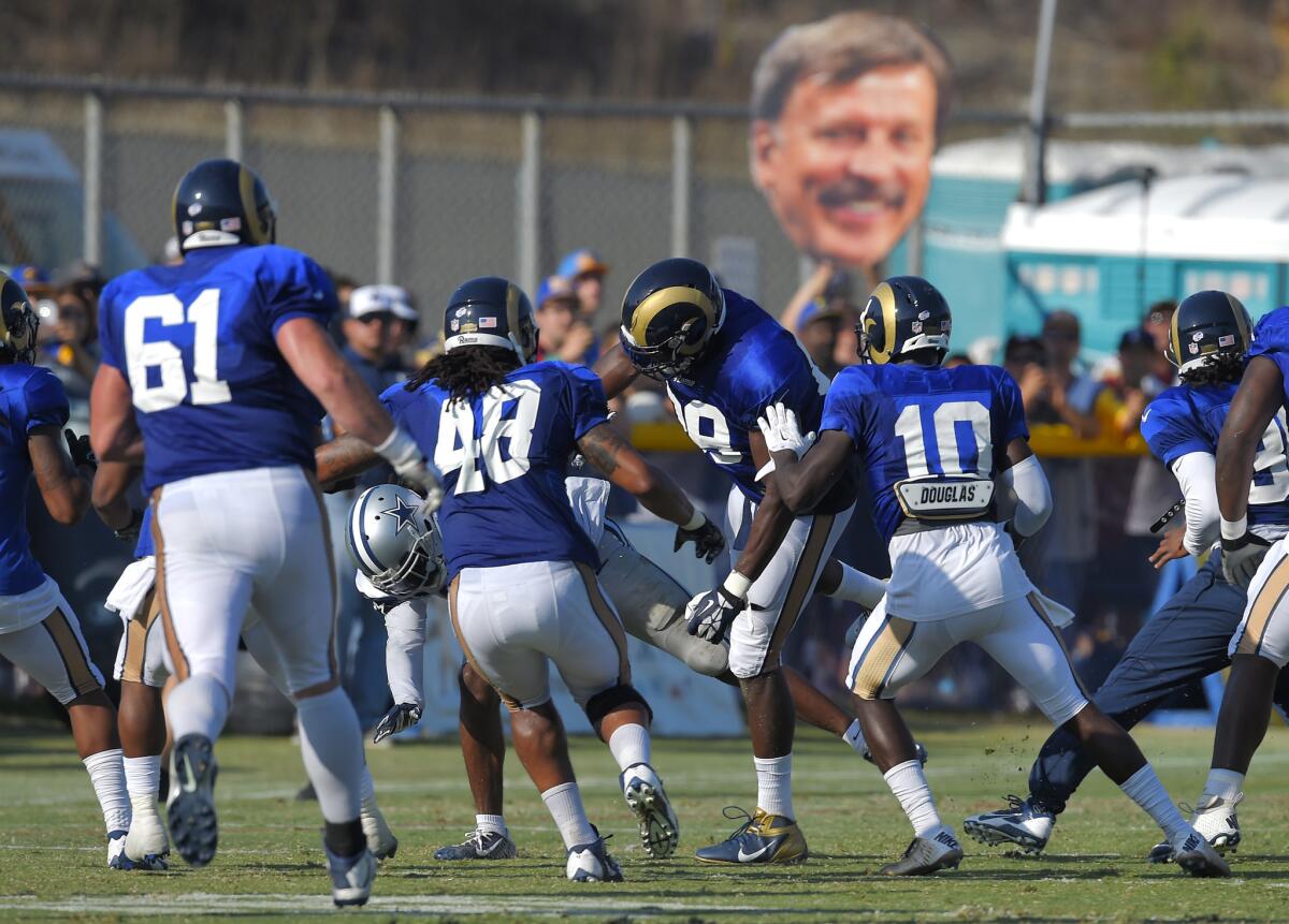 A fan holds up a cutout photo of Rams owner Stan Kroenke during a joint training camp practice between the Rams and the Dallas Cowboys in Oxnard on Aug. 18.