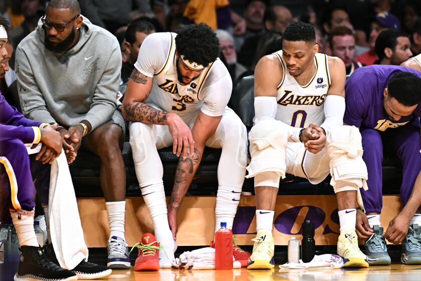 Los Angeles, California April 3, 2022- Lakers Anthony Davis, center, hold this ankle as LeBron James, let, and Russell Westbrook sit next to him against the Nuggets at Crypto.com Arena Sunday. (Wally Skalij/Los Angeles Times)