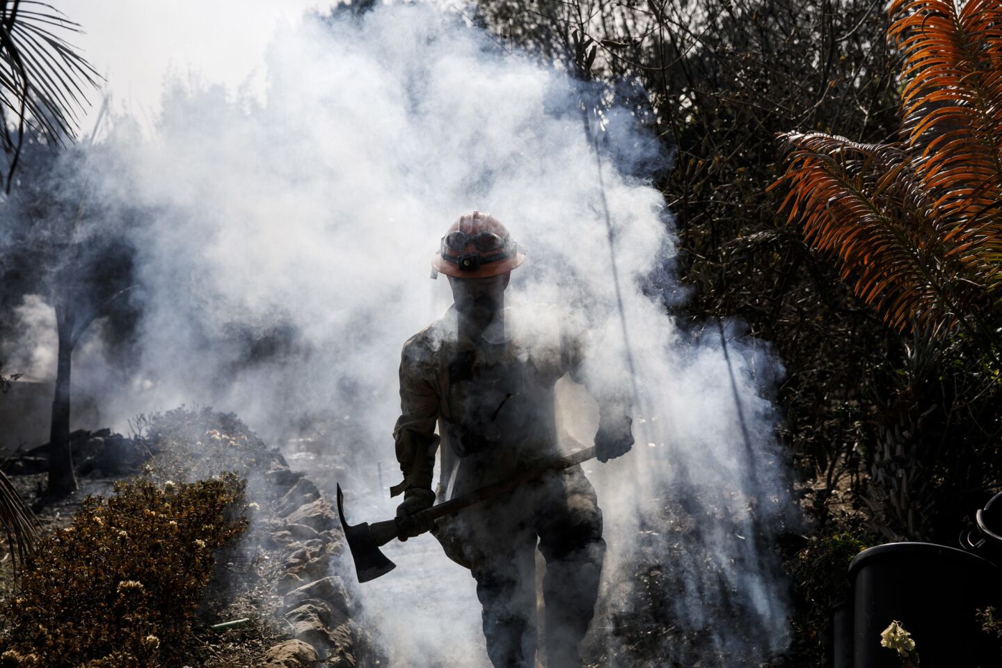 LA County firefighter Battalion 13 Captain Victor Correa helps put out hotspot in a neighborhood on Harvester road in Malibu.