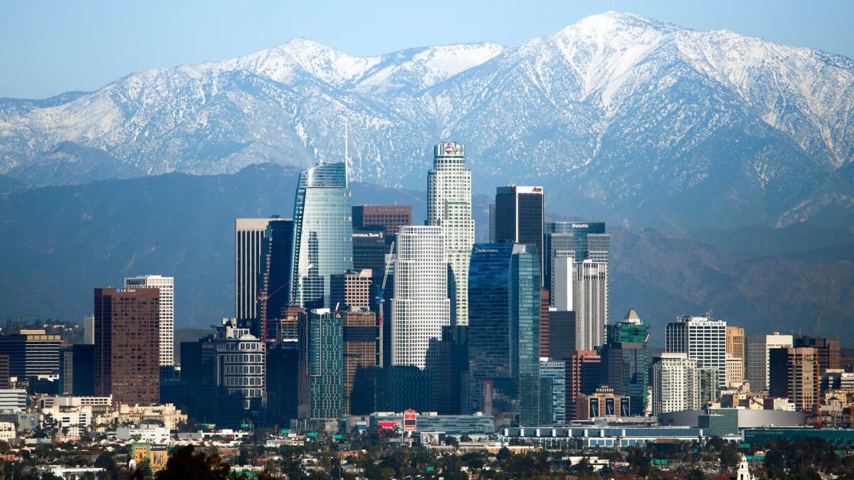 Snow-covered peaks on the San Gabriel mountains from recent storms frame the skyline of downtown Los Angeles on Dec. 27.