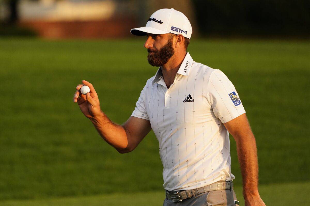 Dustin Johnson holds up his ball on the 18th green after finishing the third round of the Masters on Saturday.