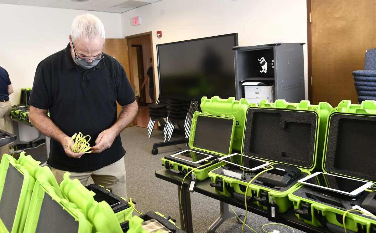 FILE - Mark Splonskowski assembles electronic poll book kits that voters will uses to sign in at polling locations at the Albany County Board of Elections building, Oct. 14, 2020, in Albany, N.Y. Attempts to develop the first-ever national standards for electronic voter rolls, the source of problems and hacking concerns in previous elections, may not be ready or available for wide use in time for the 2024 presidential election, concerning election experts. (AP Photo/Hans Pennink, File)