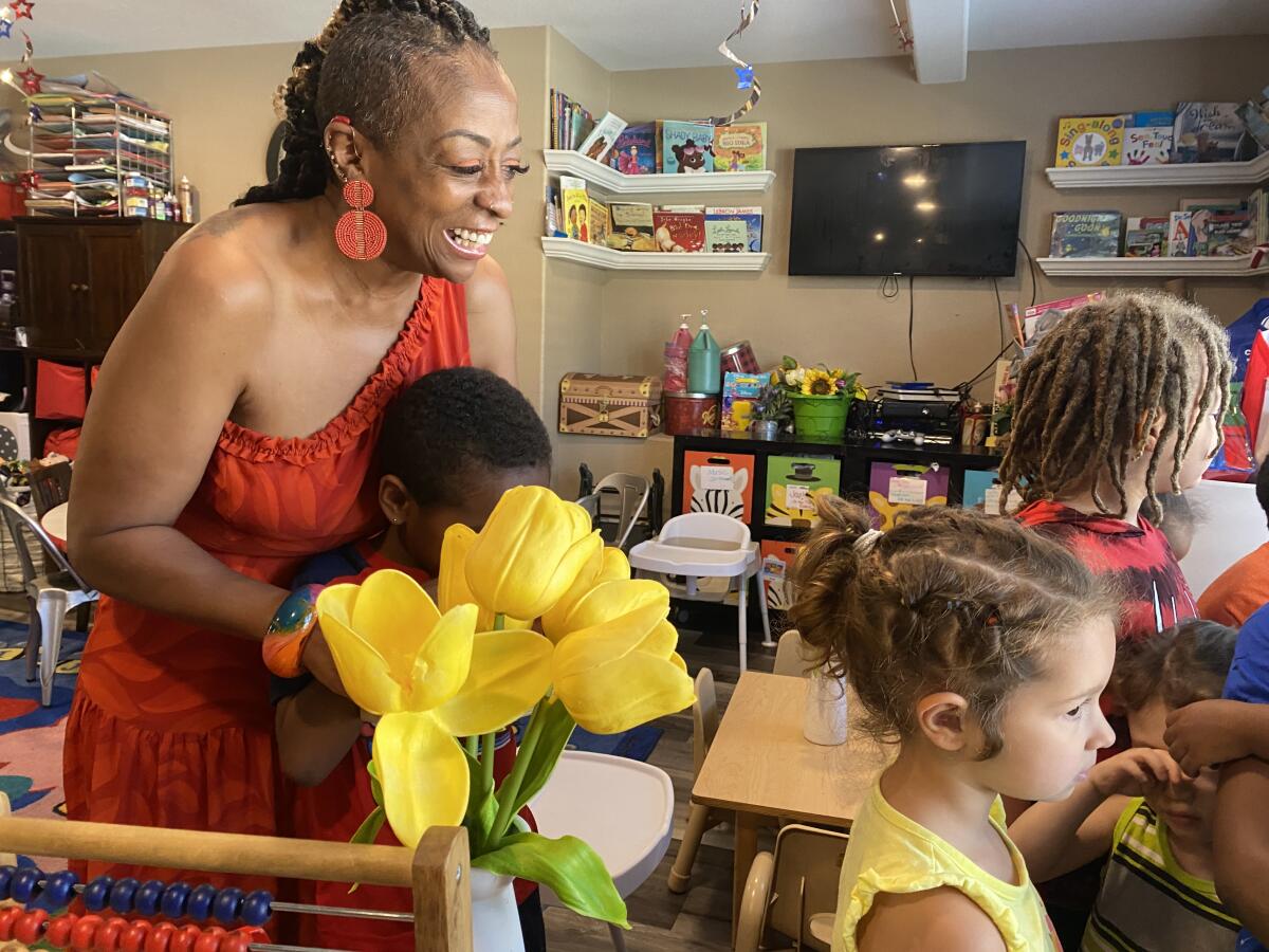 A woman smiles while looking over children at a day-care center