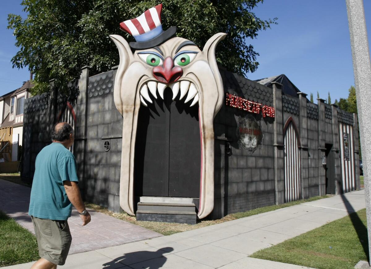 A passerby walks past the House of Fun being set up by Preston and Diane Meyer and the Rotten Apple gang at 907 N. California St. in Burbank on Thursday, Oct. 23, 2014.