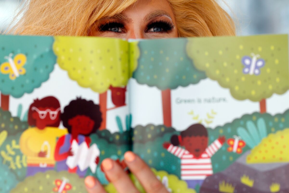 A drag queen's eyes are seen behind a children's book