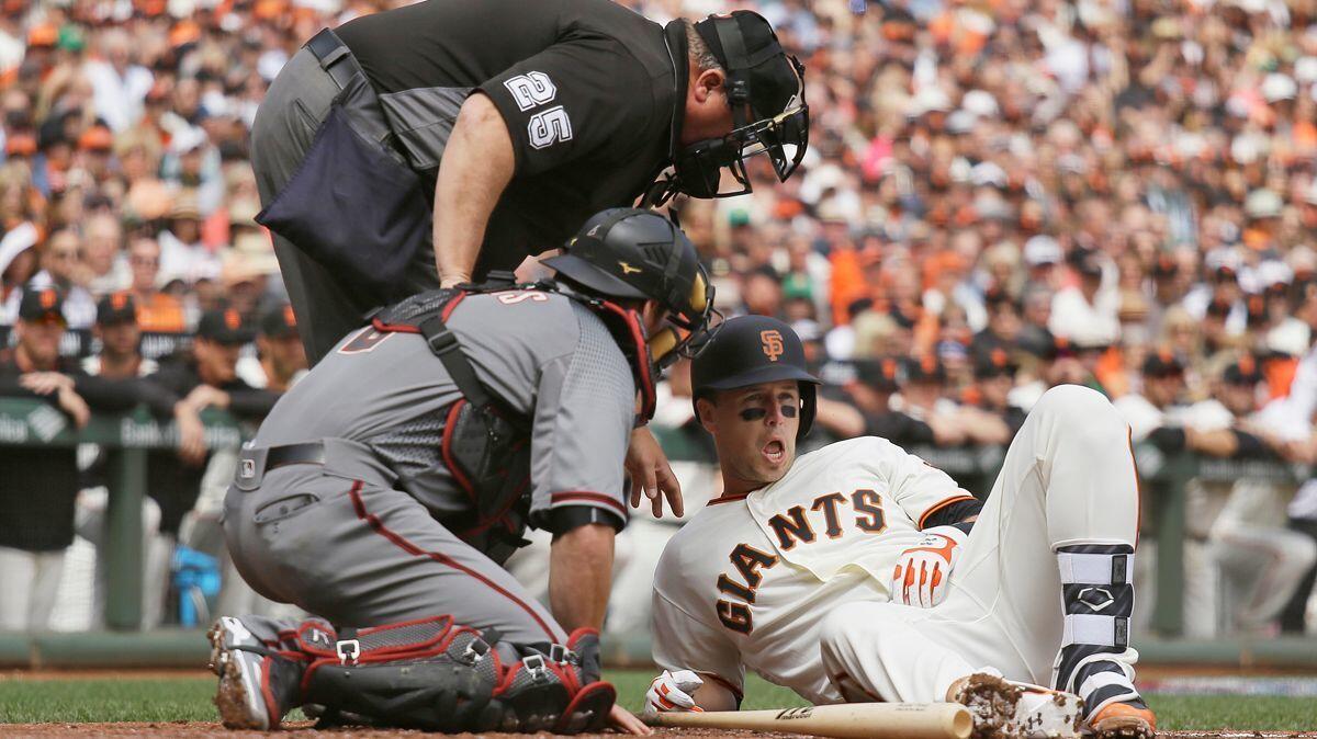 San Francisco Giants' Buster Posey, right, is looked at by home plate umpire Fieldin Culbreth and Arizona Diamondbacks catcher Jeff Mathis after getting hit in the helmet by a fastball on Monday.