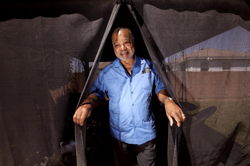 SOUTH LOS ANGELES, CA - APRIL 19, 2022 - - Former Motown singer-songwriter Larry Buford peers out from his backyard cabana at his home located across the street from the LA URM Avalon Interim Housing in Willowbrook in South Los Angeles on April 19, 2022. Buford was originally opposed to the shelter, the third senior/homeless project to go up across the street from his home, but over two years of correspondence with Andy Bales, chief executive at URM, he came to be a supporter. (Genaro Molina / Los Angeles Times)