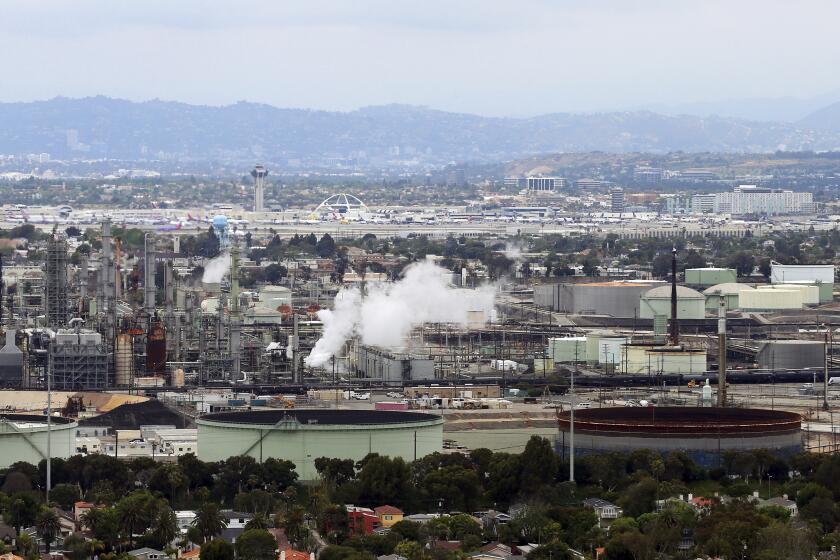 FILE - This May 25, 2017 aerial photo shows the Standard Oil Refinery in El Segundo, Calif., with Los Angeles International Airport in the background and the El Porto neighborhood of Manhattan Beach, Calif., in the foreground. A plan to extend California's cap-and-trade program for another decade looks beyond cutting greenhouse gas emissions and takes aim at toxic air in the polluted neighborhoods around refineries and factories. (AP Photo/Reed Saxon, File)