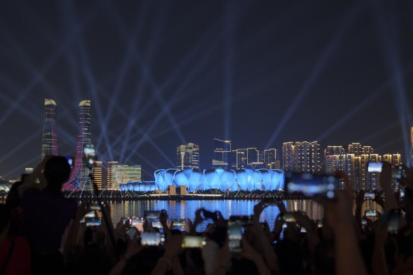 Peoples take picture of Hangzhou Olympic Sports Centre Stadium during light & show performance ahead of the 19th Asian Games along riverside in Hangzhou, China, Tuesday, Sept. 19, 2023. The Asian Games are set to go in China. It's the biggest multi-sport international event in the country since pandemic restrictions were lifted there about nine months ago. (AP Photo/Vincent Thian)