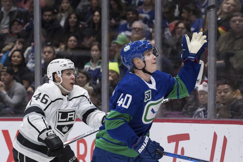 Vancouver Canucks' Elias Pettersson, right, of Sweden, reaches to catch the puck in front of Los Angeles Kings' Blake Lizotte during the third period of an NHL hockey game Saturday, Dec. 28, 2019, in Vancouver, British Columbia. (Darryl Dyck/The Canadian Press via AP)