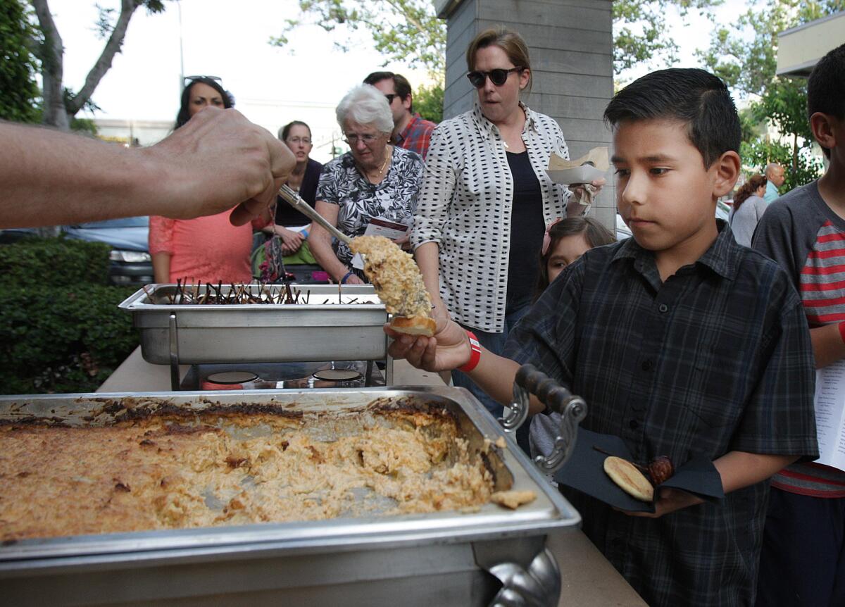 In this April 2015 photo, David Martinez, of Glendale, is served hot artichoke dip from The Spot Gourmet Catering at A Taste of Downtown Glendale, presented by Glendale Healthy Kids.