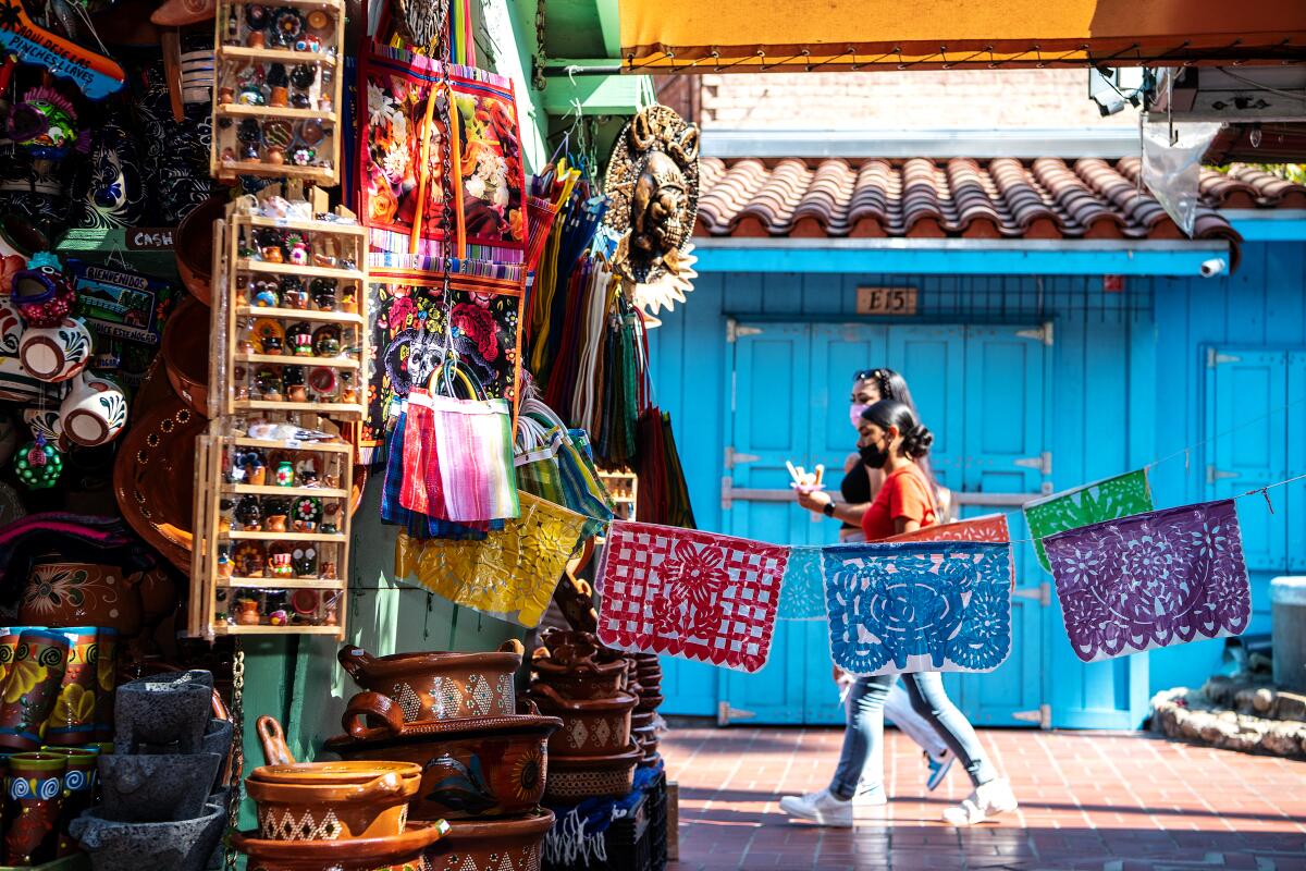 Two people walk by a shop on Olvera Street