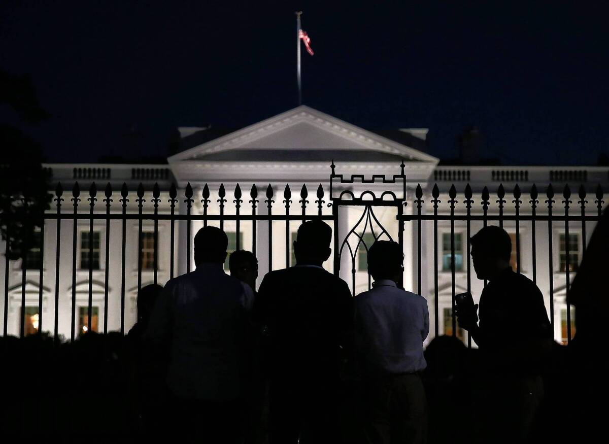 People stand in front of the White House on Monday evening, a few hours before the much of the federal government shut down midnight Tuesday.