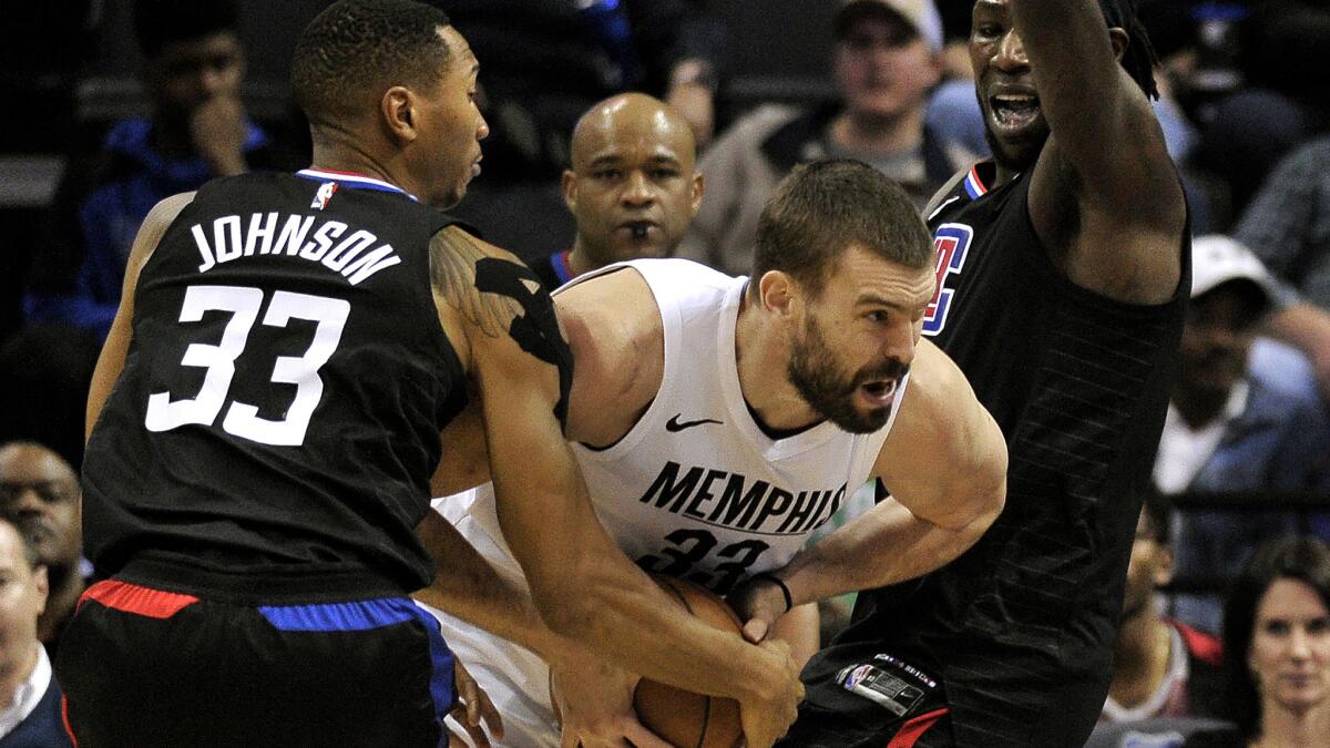 Clippers forwards Wesley Johnson, left, and Montrezl Harrell trap Grizzlies center Marc Gasol with their double-team defense.