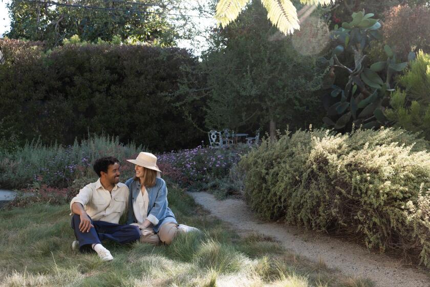 Los Angeles, CA - June 20: Phoebe Novack and Brian Auggrey pose for a portrait in the backyard of their home that they call "Chateau Chaparral," on Saturday, June 20, 2026, in Los Angeles, California. They purchased a small home and re-designed the back yard themselves into a native plant sanctuary. It's been on the Theodore Payne garden tour each of the last two years. (Dania Maxwell/ For The Times)