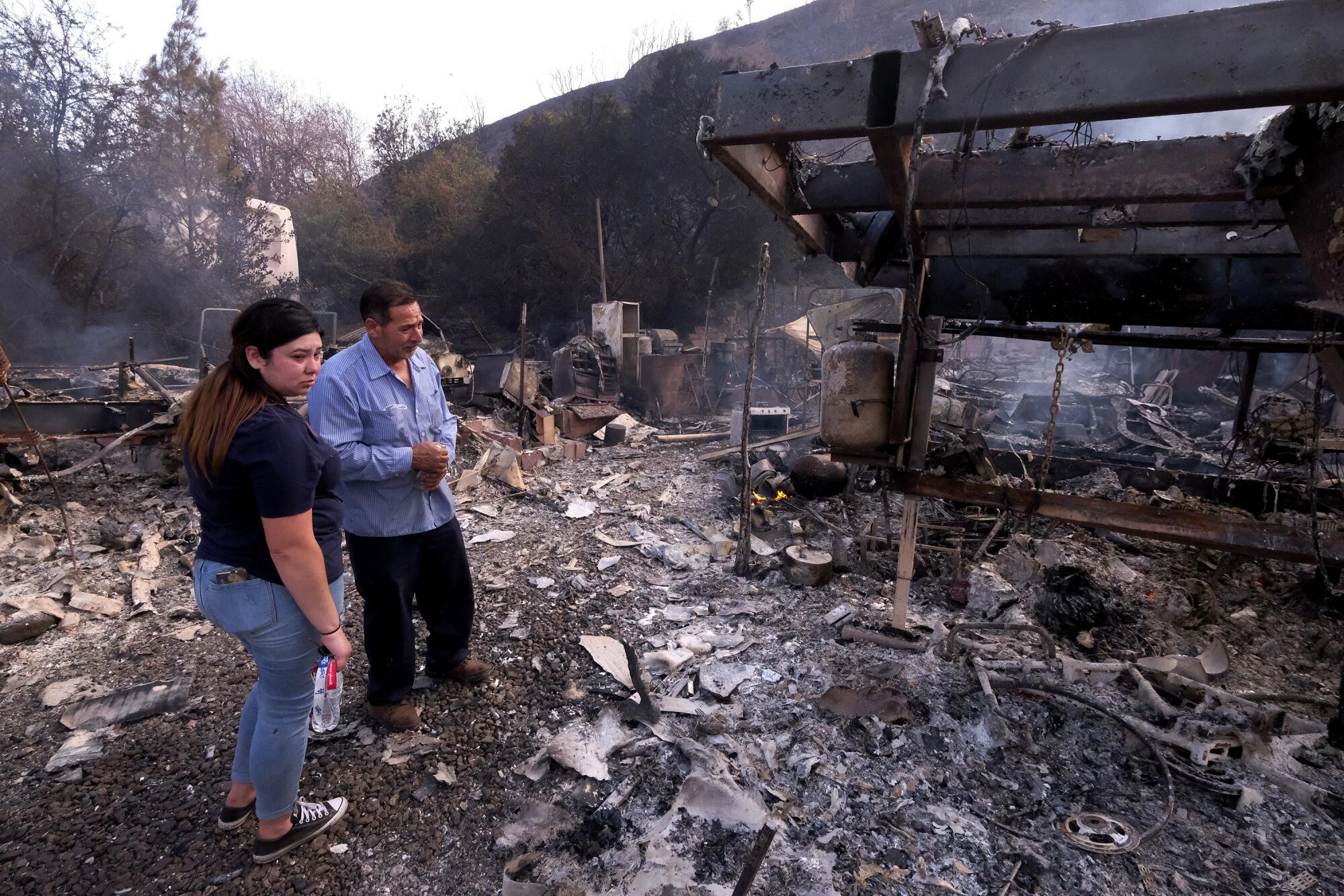 Jose Lamas and his daughter Astrid Covarrubias survey the charred debris of his burned-out home from the South fire 