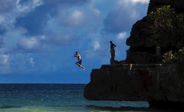 A visitor jumps into the Atlantic, where Barbados' coastline is rocky and its ocean dramatic. On the Caribbean side of the island, the sea is turquoise and tranquil.