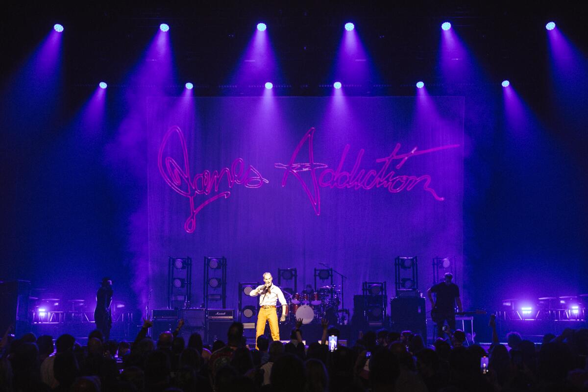 Jane's Addiction onstage underneath a banner in script that says "Jane's Addiction"