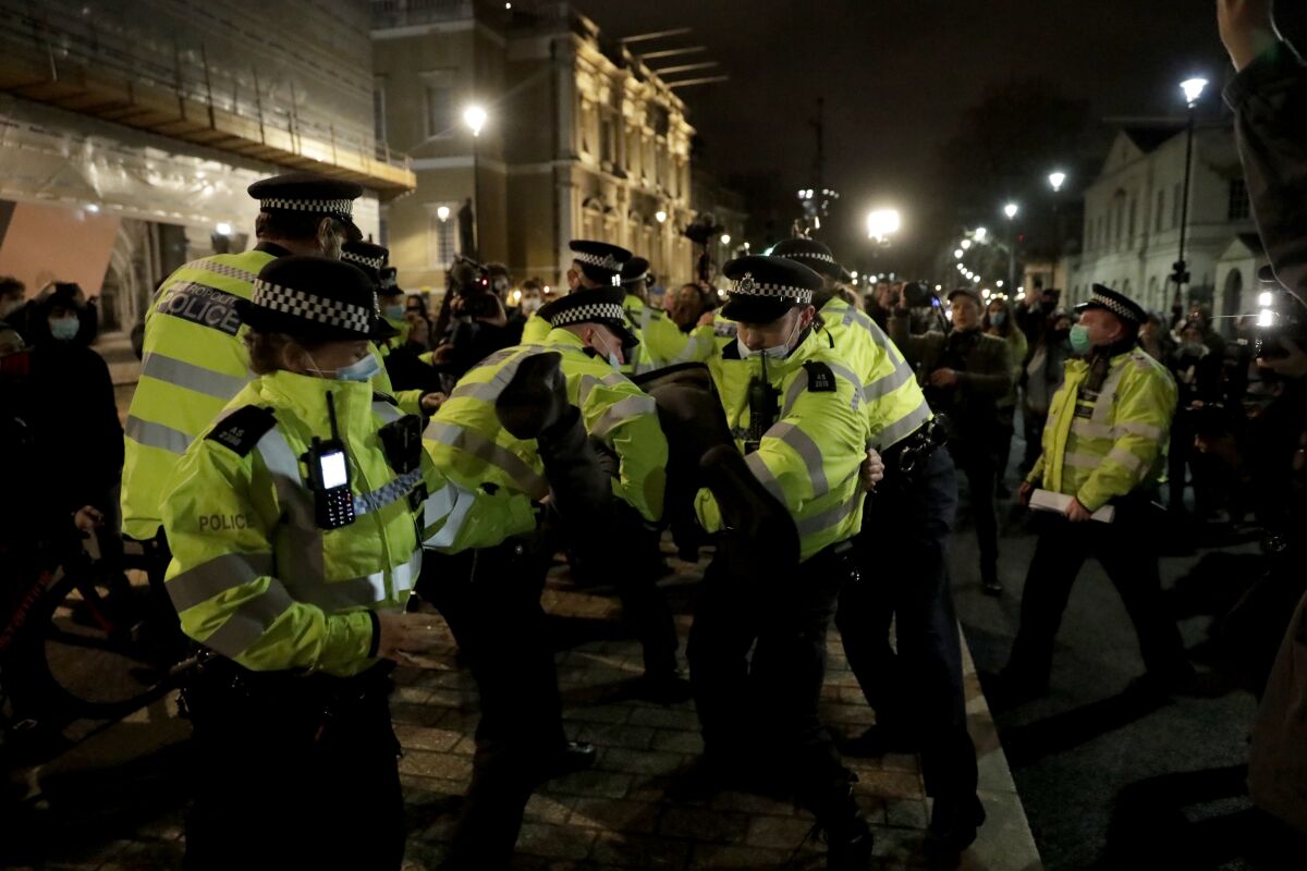 FILE - Police officers restrain a man after they told people to go home during a march to reflect on the murder of 33-year old marketing executive, Sarah Everard, in London, on March 15, 2021. The way police handled a vigil in memory of a murdered woman, held during Britain’s coronavirus lockdown, breached organizers’ rights to free speech and assembly, a court ruled Friday, March 11, 2022. The protest vigil was called after Sarah Everard, a 33-year-old London woman, was abducted and murdered in March 2021 by an off-duty Metropolitan Police officer as she walked home at night. (AP Photo/Matt Dunham)