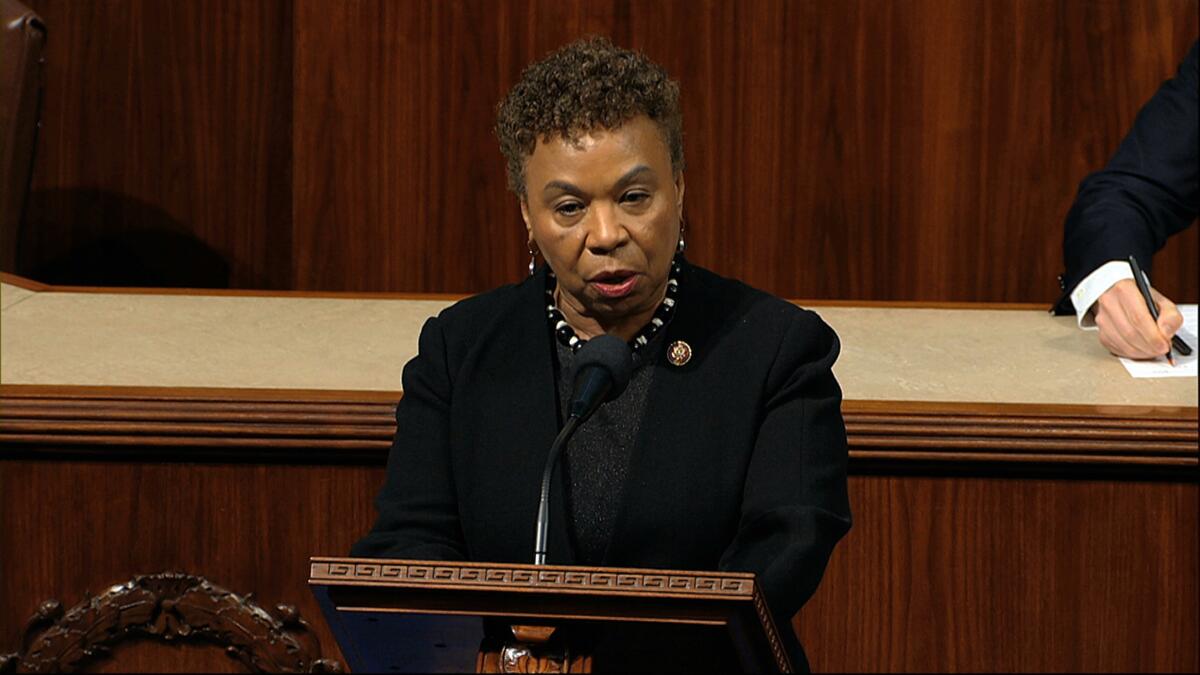 Barbara Lee stands at a lectern.