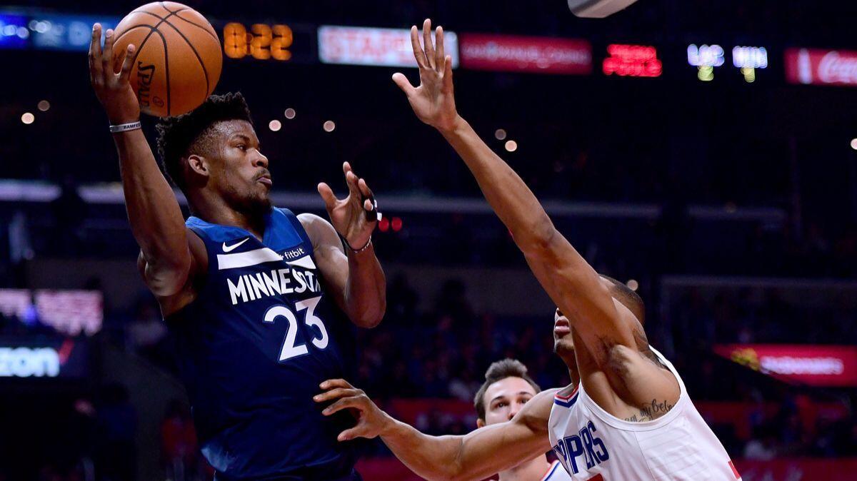 Minnesota Timberwolves' Jimmy Butler (23) passes around Clippers' Wesley Johnson (33) and Danilo Gallinari (8) during the first half at Staples Center on Wednesday.