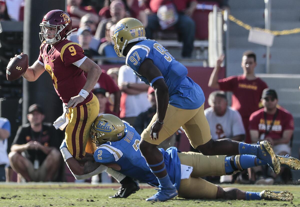 UCLA linebacker Josh Woods (2) tackles USC quarterback Kedon Slovis (9) during a fourth quarter drive at the Coliseum on Saturday.