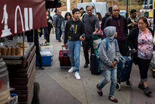Tijuana, Baja California - May 19: Anirudh Singh, 12, center with red suitcase, escorted by lawyer Glen Raj, just behind him, looks around at vendors and lines of people, as he crosses into Tijuana from San Ysidro, CA, to visit his father, Dr. Pradyuman Singh, who has been living at the Quartz Hotel & Spa in aTijuana, Baja California, since January, photographed Friday, May 19, 2023. Dr. Singh is only able to be visited by his son, as he is the only U.S. citizen in the family, brought across the border by Singh's lawyer, Glen Raj. Singh is hoping for a change in his immigration status and being able to be reunited with his family living in Laguna Niguel, CA, (Jay L. Clendenin / Los Angeles Times)