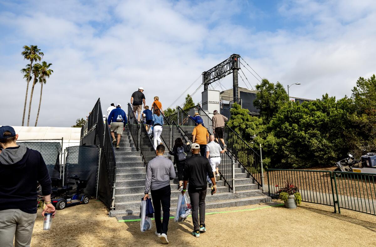 Fans cross a temporary bridge over Wilshire Boulevard after attending a practice round of the U.S. Open.