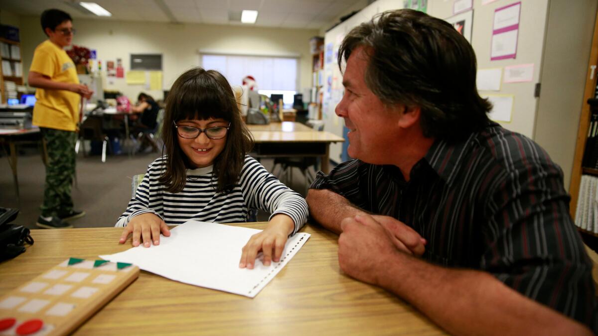 Keith Christian, right, instructs Mina Lamarra, 8, center, at Barton Elementary.