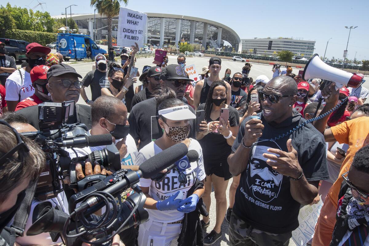 Pro Football Hall of Famer Terrell Owens, right, addresses protesters outside Sofi Stadium in Inglewood on  Thursday.